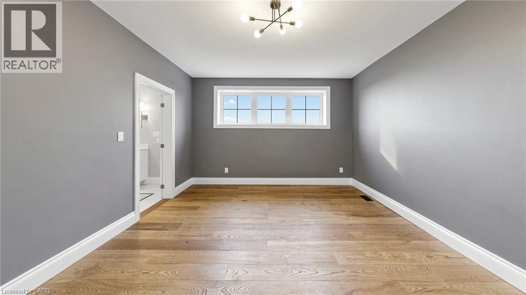 Spacious room featuring wood-finish flooring, neutral gray walls, and white baseboards - 41 Talbot Road, Delhi, ON - Indoor Photo Showing Other Room