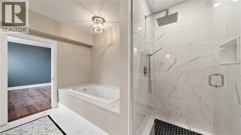Contemporary bathroom featuring a spacious walk-in shower with a rainfall showerhead, glass enclosure, and white marble-look tile walls - 41 Talbot Road, Delhi, ON - Indoor Photo Showing Bathroom
