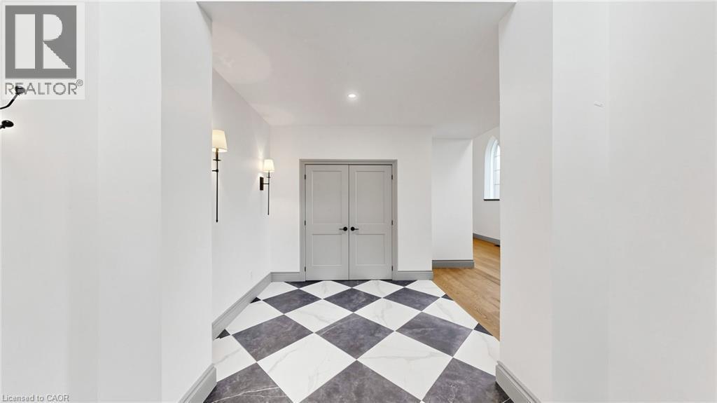 Entryway featuring a black and white checkered floor, two wall sconces, a pair of paneled doors, and a recessed ceiling light - 41 Talbot Road, Delhi, ON - Indoor