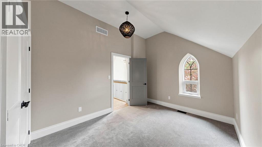 Room featuring vaulted ceilings, a unique arched window, gray carpeting, neutral wall tones, and contrasting white trim - 41 Talbot Road, Delhi, ON - Indoor Photo Showing Other Room