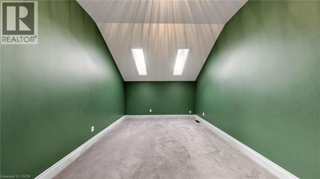 Carpeted room with a vaulted ceiling, twin skylights, green painted walls, and white baseboards - 41 Talbot Road, Delhi, ON - Indoor Photo Showing Other Room