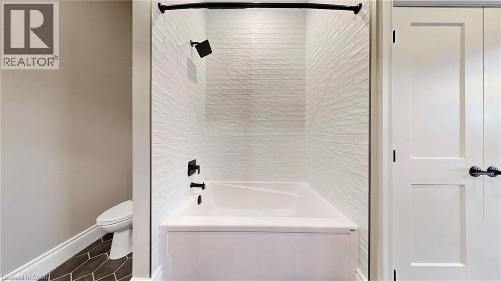 White subway tile shower surround with textured finish, featuring matte black fixtures and a white tub - 41 Talbot Road, Delhi, ON - Indoor Photo Showing Bathroom