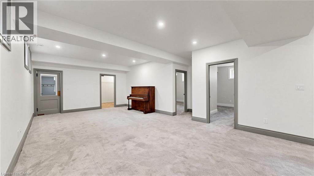 Expansive carpeted room featuring recessed lighting, multiple doorways with grey trim, and white painted walls - 41 Talbot Road, Delhi, ON - Indoor