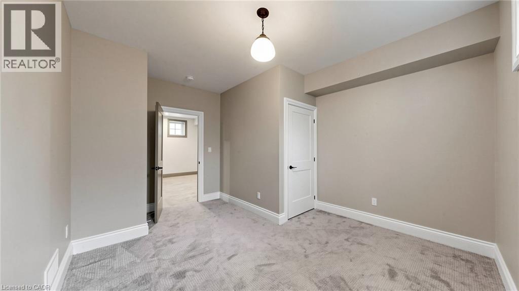 Spacious room featuring neutral wall tones, light gray patterned carpeting, white baseboards, and white interior doors with black hardware - 41 Talbot Road, Delhi, ON - Indoor Photo Showing Other Room