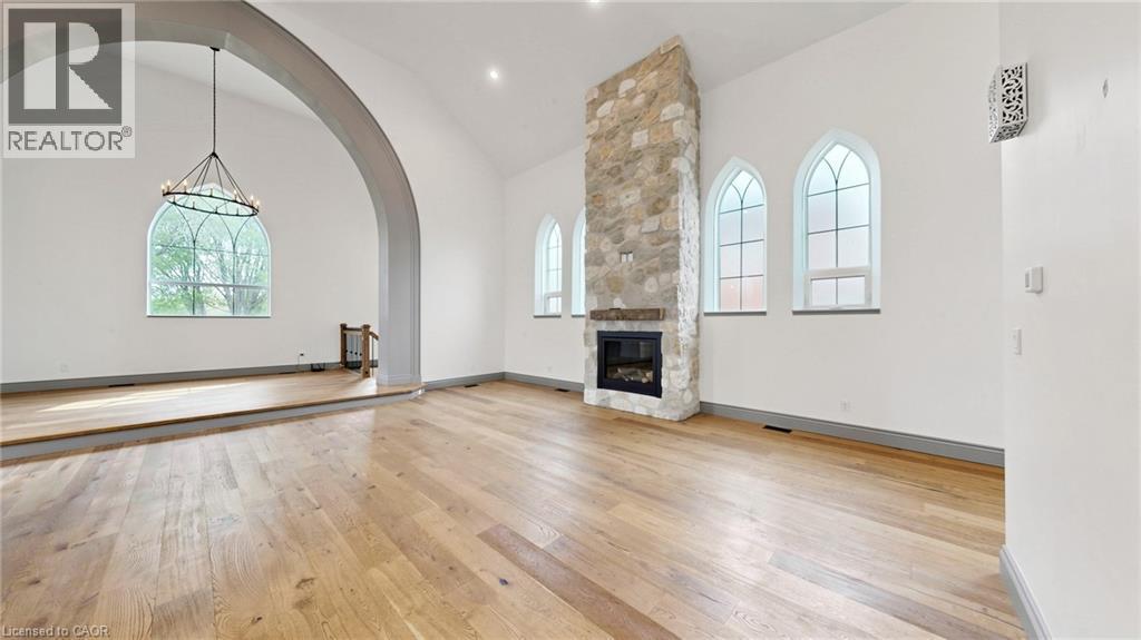 Expansive interior space featuring wood-finish flooring, a vaulted ceiling, and a prominent stone-clad fireplace with a built-in firebox - 41 Talbot Road, Delhi, ON - Indoor With Fireplace