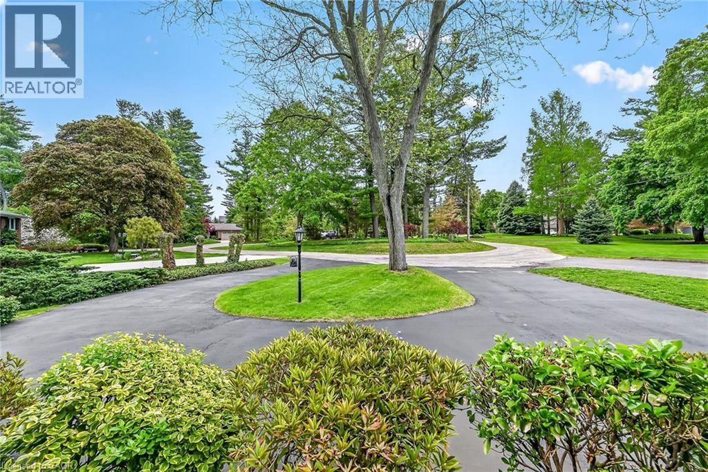 Expansive circular driveway with mature landscaping, a central lawn island, and a prominent streetlamp - 2 Summit Circle, Simcoe, ON - Outdoor With View