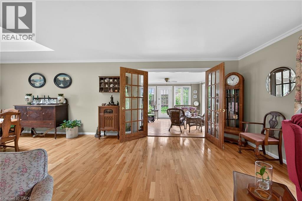 Hardwood flooring throughout featuring a pair of glass-paneled doors with numerous windows towards forrest - 2 Summit Circle, Simcoe, ON - Indoor Photo Showing Other Room