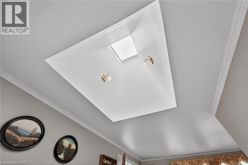 Ceiling featuring a recessed skylight, two wall sconces with brass-finish accents, and crown molding - 2 Summit Circle, Simcoe, ON - Indoor Photo Showing Other Room