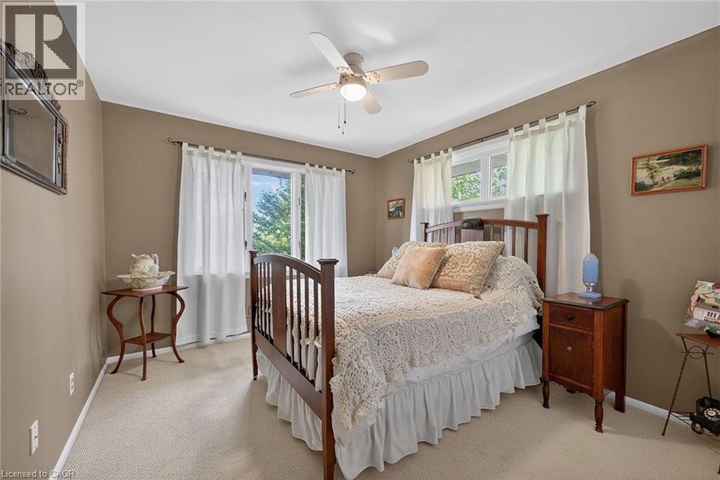 Bedroom featuring neutral-toned walls, light-colored carpeting, a ceiling fan with integrated lighting, and a window with white curtains - 2 Summit Circle, Simcoe, ON - Indoor Photo Showing Bedroom