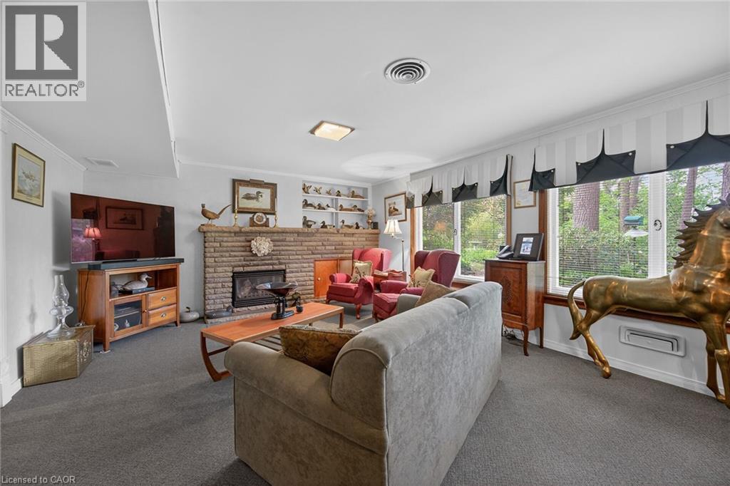 Living area featuring a brick-faced fireplace with a hearth, wall-to-wall carpeting, and multiple windows - 2 Summit Circle, Simcoe, ON - Indoor Photo Showing Living Room With Fireplace