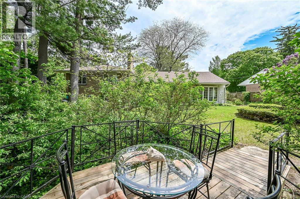 Wood-finish deck with decorative metal railings offering an elevated perspective of the expansive backyard - 2 Summit Circle, Simcoe, ON - Outdoor