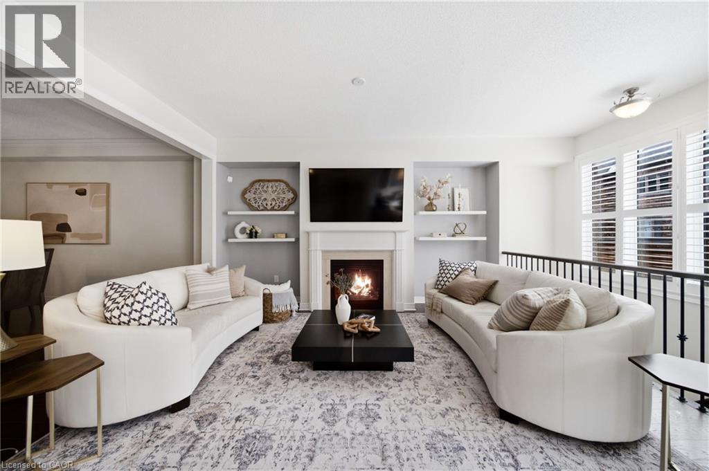 Living area featuring a fireplace with a white mantel, built-in shelving, white plantation shutters, and an open railing - 2466 Village Common, Oakville, ON - Indoor Photo Showing Living Room With Fireplace