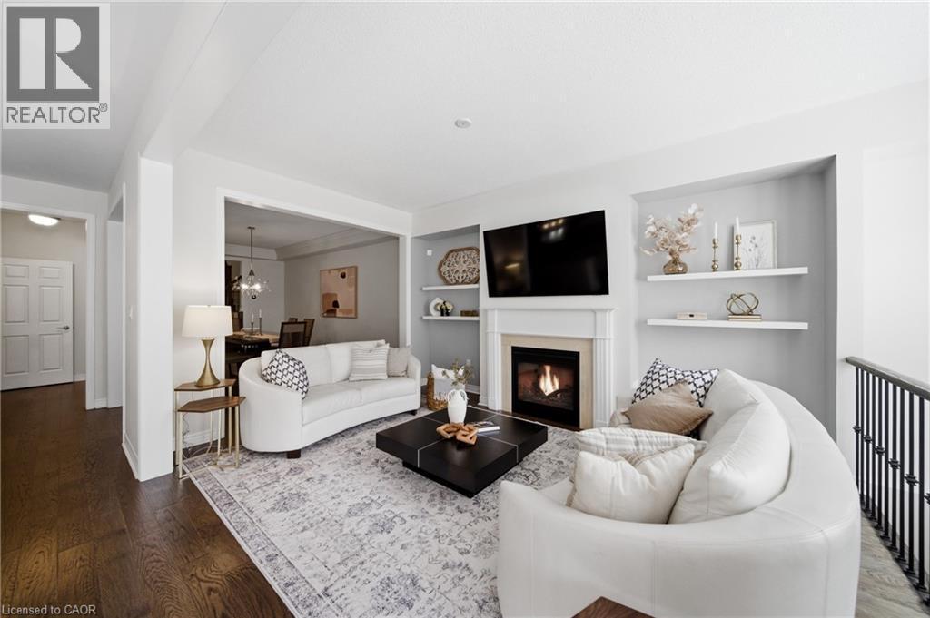 Living room featuring a fireplace with a mantel, built-in shelving, wood-finish flooring, and a railing - 2466 Village Common, Oakville, ON - Indoor Photo Showing Living Room With Fireplace