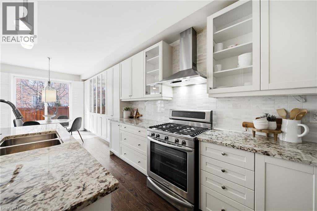 Contemporary kitchen featuring light-colored cabinetry, stainless steel appliances, dark wood-finish flooring, and speckled countertops - 2466 Village Common, Oakville, ON - Indoor Photo Showing Kitchen With Double Sink With Upgraded Kitchen