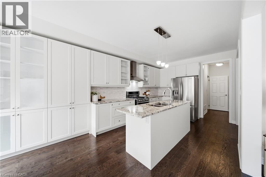 Open-concept kitchen featuring an island with a double basin sink and a contemporary pendant light fixture - 2466 Village Common, Oakville, ON - Indoor Photo Showing Kitchen With Stainless Steel Kitchen With Double Sink With Upgraded Kitchen