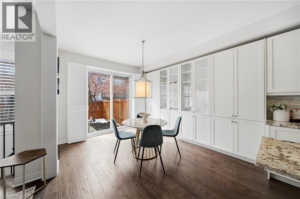 Dining area featuring rich wood-finish flooring and extensive white cabinetry, including glass-front display cabinets - 2466 Village Common, Oakville, ON - Indoor Photo Showing Dining Room