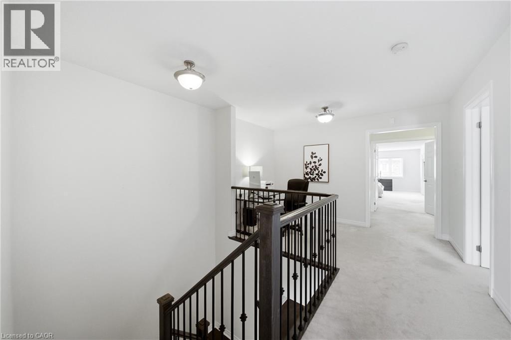 Upper-level landing featuring a wood staircase with wrought iron balusters, light gray carpet flooring, and recessed lighting - 2466 Village Common, Oakville, ON - Indoor Photo Showing Other Room
