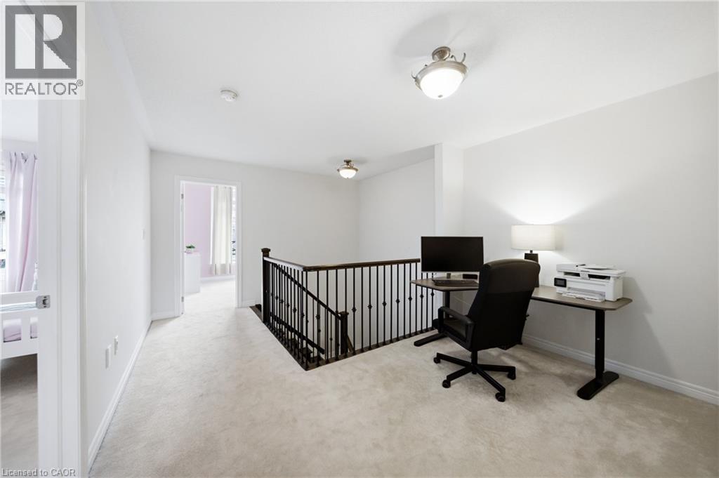 Carpeted landing featuring a wrought iron and wood baluster railing, flush-mount ceiling lighting, and a white interior paint palette - 2466 Village Common, Oakville, ON - Indoor Photo Showing Office