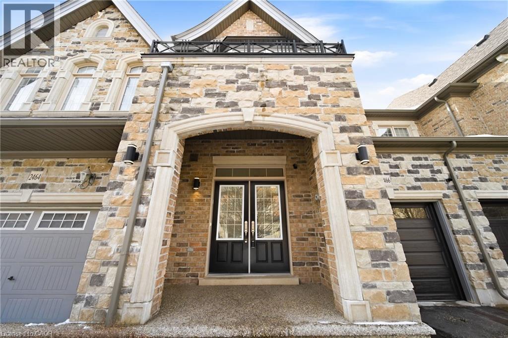 Stone and brick facade featuring a covered entry, black double doors with transom windows, and exterior wall sconces - 2466 Village Common, Oakville, ON - Outdoor