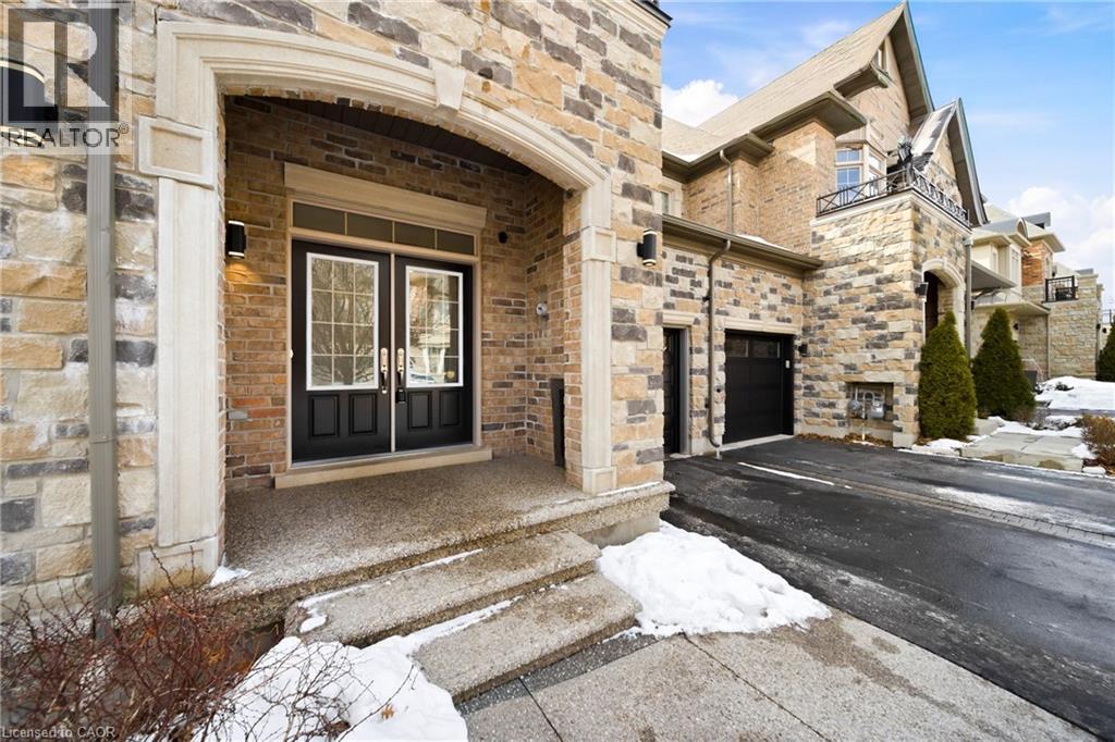 Stone and brick exterior featuring a double-door entry with transom windows, covered porch, and exterior sconce lighting - 2466 Village Common, Oakville, ON - Outdoor With Facade