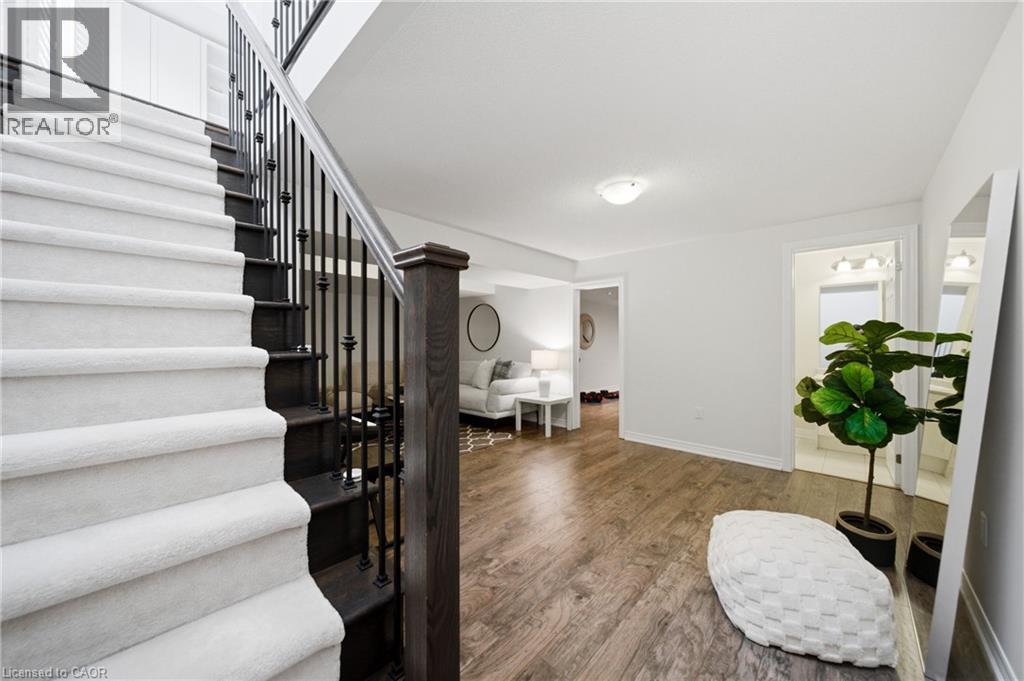 Entry foyer with wood-finish flooring, a carpeted staircase featuring wrought iron balusters, and a recessed ceiling light - 2466 Village Common, Oakville, ON - Indoor Photo Showing Other Room
