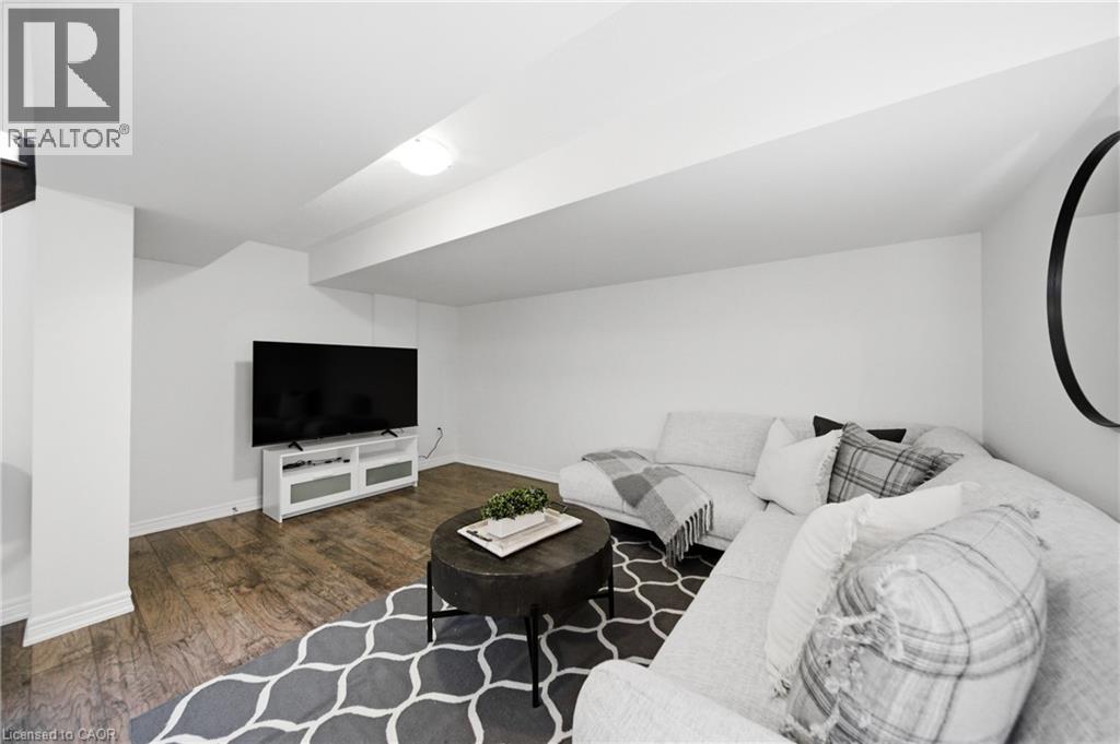 Finished lower-level entertainment space featuring wood-finish flooring, white walls, and recessed lighting - 2466 Village Common, Oakville, ON - Indoor Photo Showing Other Room