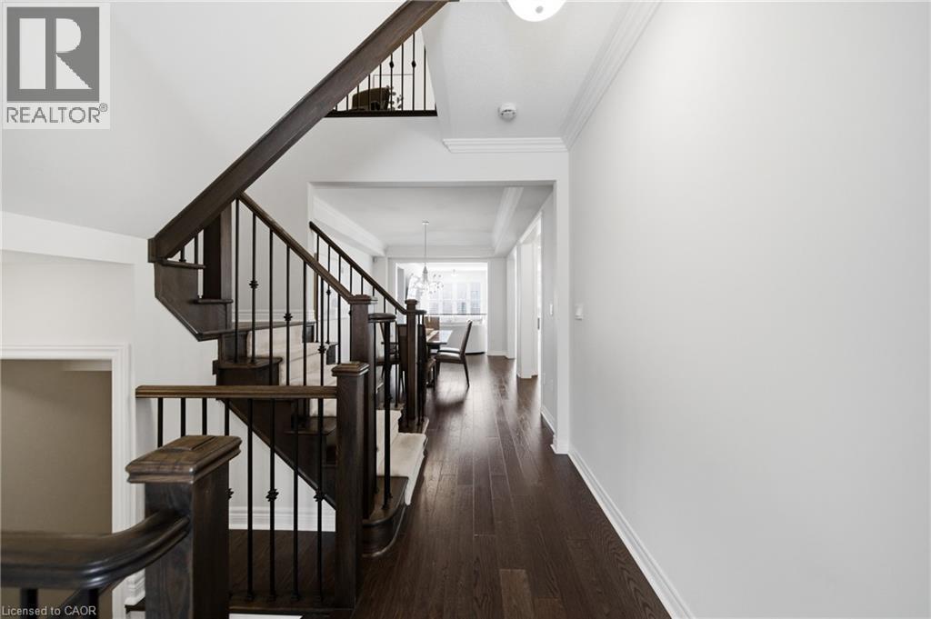 Multi-level staircase featuring dark wood newel posts and railings with decorative wrought iron balusters - 2466 Village Common, Oakville, ON - Indoor Photo Showing Other Room