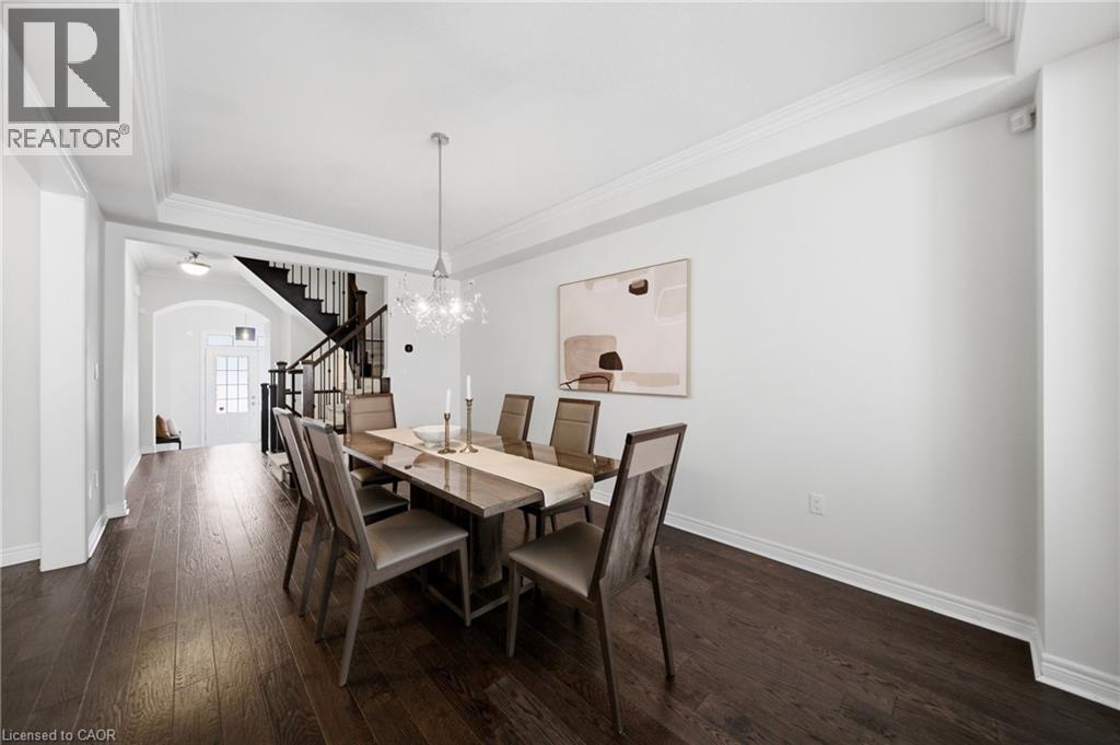Formal dining area featuring dark wood-finish flooring, white crown molding, and a contemporary chandelier - 2466 Village Common, Oakville, ON - Indoor Photo Showing Dining Room