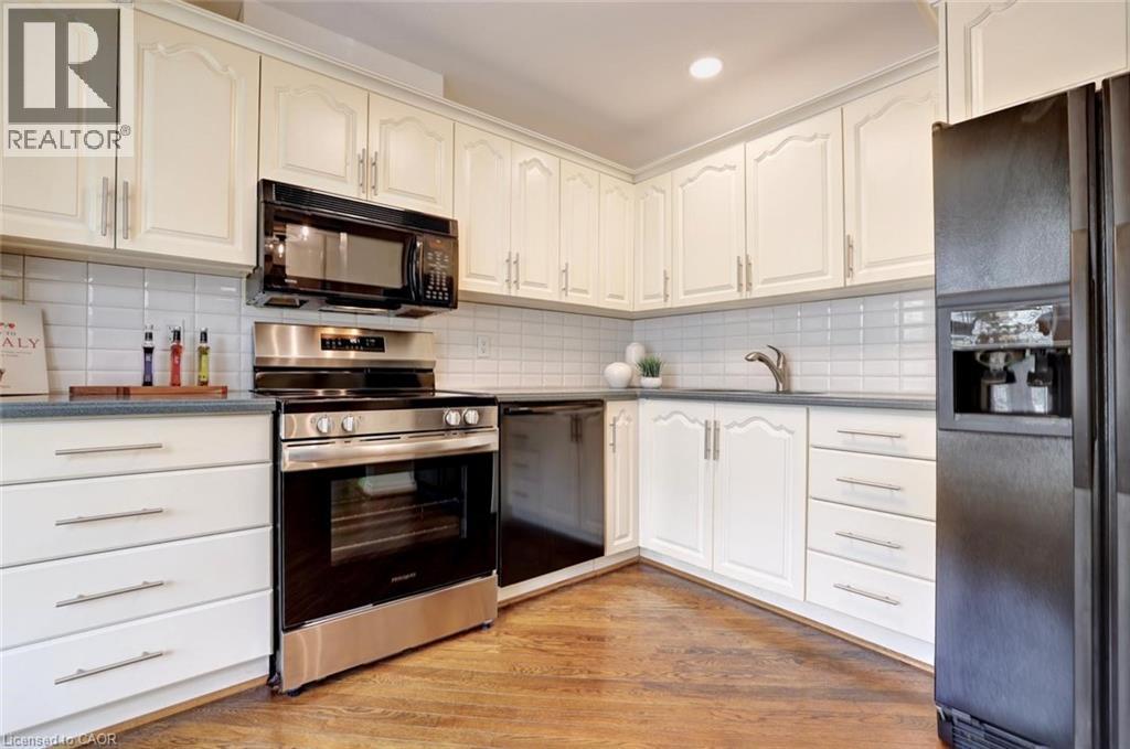 Kitchen featuring cream-colored cabinetry with decorative molding, a subway tile backsplash, and dark countertops - 463 Blathwayte Lane, Burlington, ON - Indoor Photo Showing Kitchen