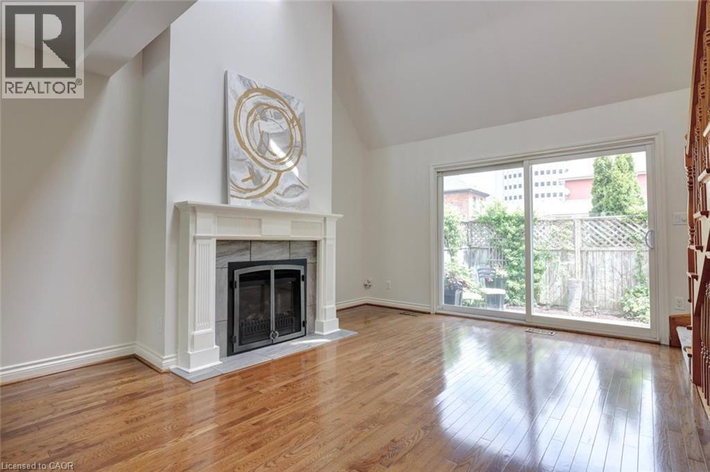 Living area featuring hardwood flooring, a fireplace with a white mantel and stone surround, and a vaulted ceiling - 463 Blathwayte Lane, Burlington, ON - Indoor Photo Showing Living Room With Fireplace