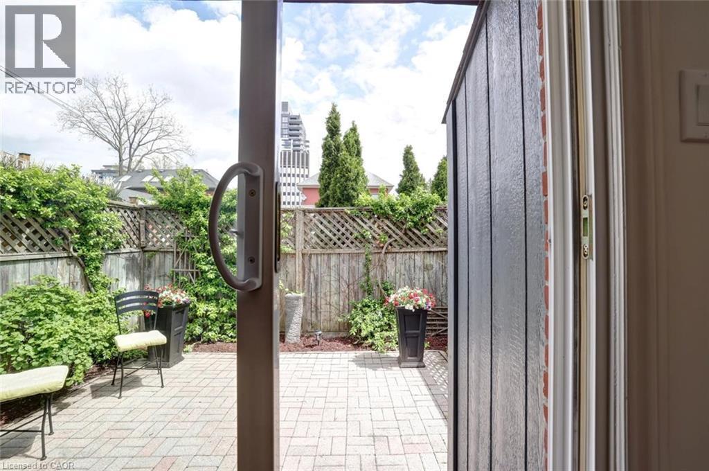 Patio area featuring brick pavers, perimeter fencing with lattice detailing, and established shrubbery - 463 Blathwayte Lane, Burlington, ON - Outdoor