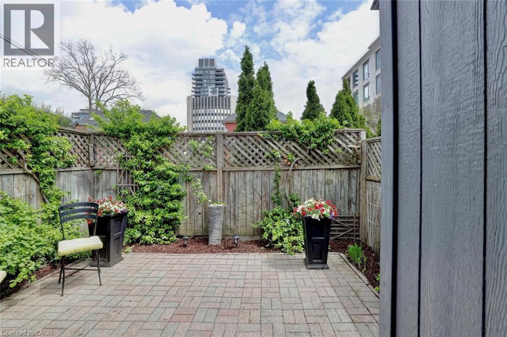 Paved patio area featuring brick-patterned pavers, a wood privacy fence, and mature perimeter greenery - 463 Blathwayte Lane, Burlington, ON - Outdoor