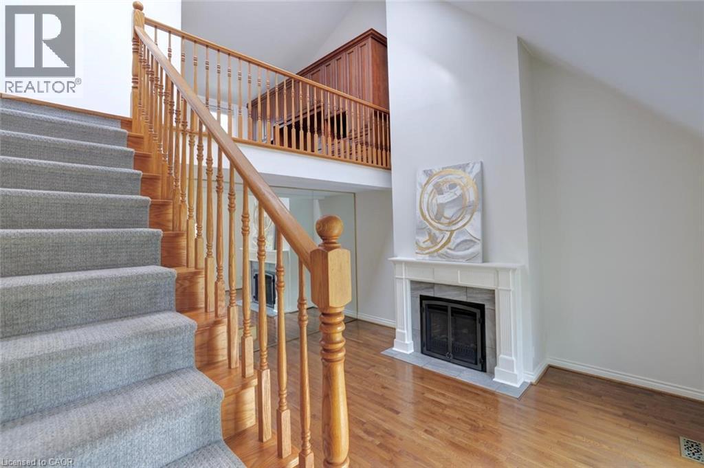 Hardwood flooring complemented by a carpeted staircase with wood banister - 463 Blathwayte Lane, Burlington, ON - Indoor Photo Showing Other Room With Fireplace