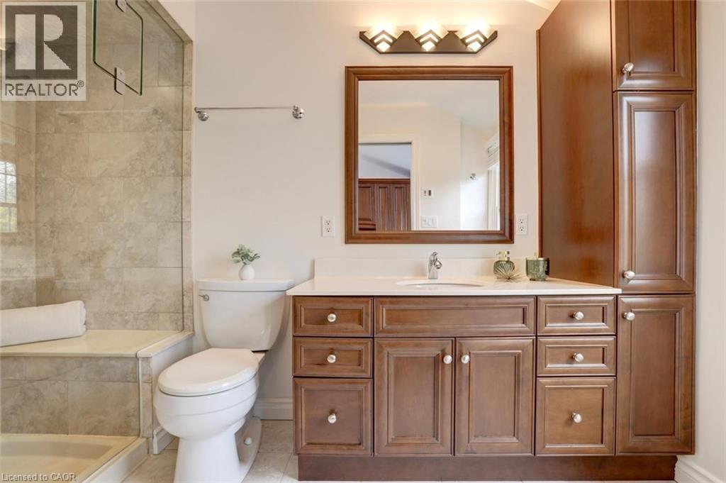 Bathroom featuring a wood-finish vanity with a light-colored countertop, integrated sink, and wall-mounted mirror - 463 Blathwayte Lane, Burlington, ON - Indoor Photo Showing Bathroom