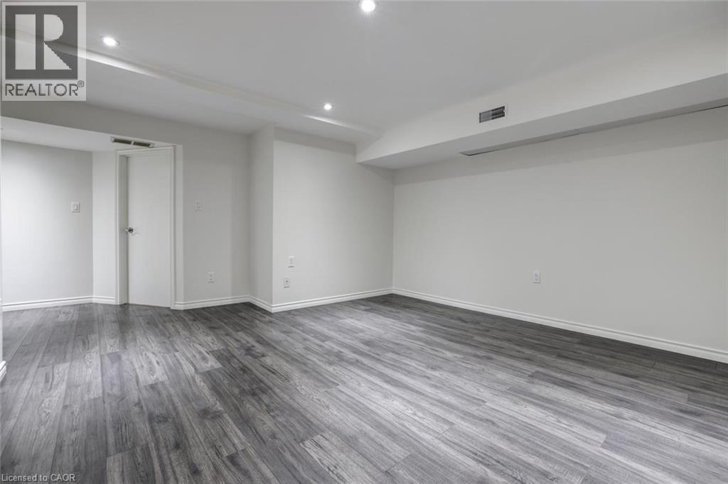 Spacious room featuring wood-finish flooring, recessed lighting, white walls, and white baseboards - 463 Blathwayte Lane, Burlington, ON - Indoor