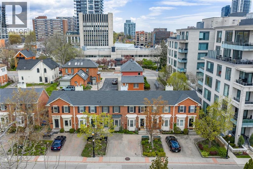 Brick townhomes featuring individual bay windows, black shutters, private driveways, and landscaped front entries - 463 Blathwayte Lane, Burlington, ON - Outdoor With Facade