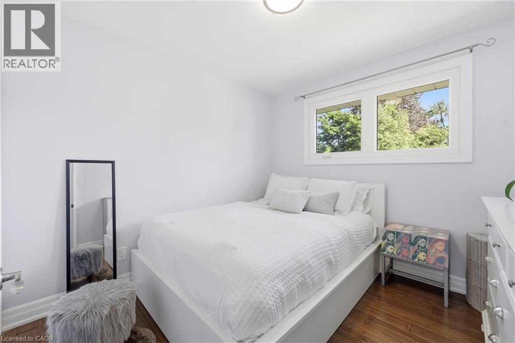 Light-filled room featuring wood-finish flooring, white trim, and a window with a treed outlook - 168 Nugent Drive, Hamilton, ON - Indoor Photo Showing Bedroom