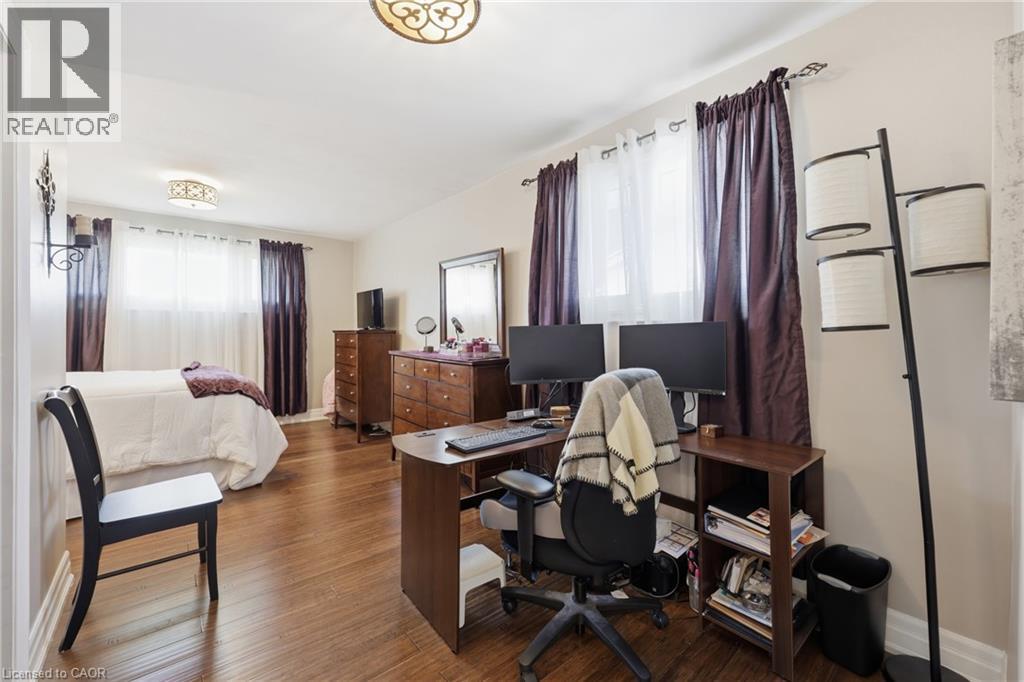 Spacious room featuring wood-finish flooring, light-toned walls, and multiple windows - 168 Nugent Drive, Hamilton, ON - Indoor