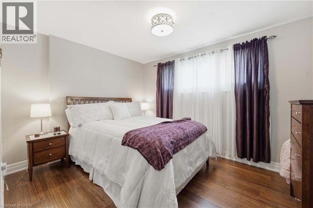 Bedroom featuring wood-finish flooring, a light neutral wall color, and a decorative ceiling light fixture - 168 Nugent Drive, Hamilton, ON - Indoor Photo Showing Bedroom