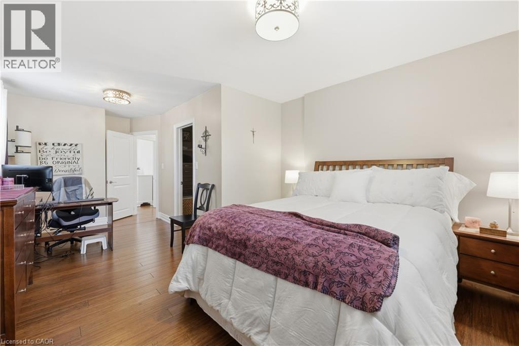 Hardwood-finish flooring throughout, featuring two ceiling-mounted light fixtures - 168 Nugent Drive, Hamilton, ON - Indoor Photo Showing Bedroom