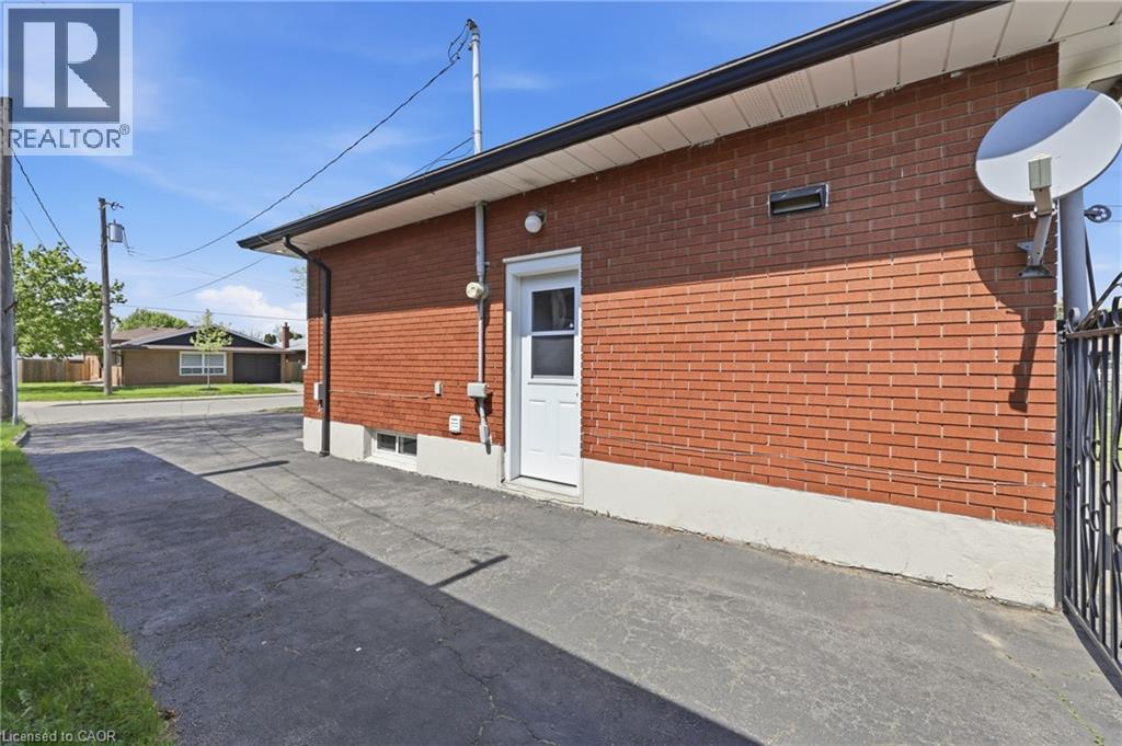 Red brick exterior with white trim, featuring a white entry door with a privacy screen - 168 Nugent Drive, Hamilton, ON - Outdoor With Exterior