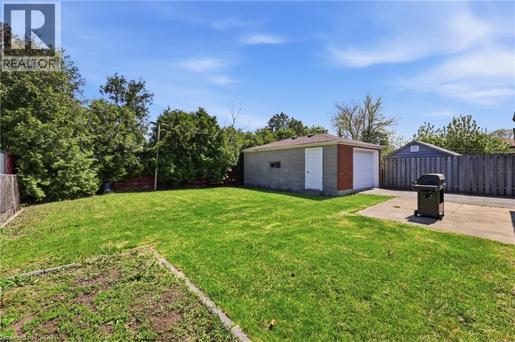 Expansive rear yard featuring a detached two-car garage with brick siding, a privacy fence, and mature perimeter trees - 168 Nugent Drive, Hamilton, ON - Outdoor