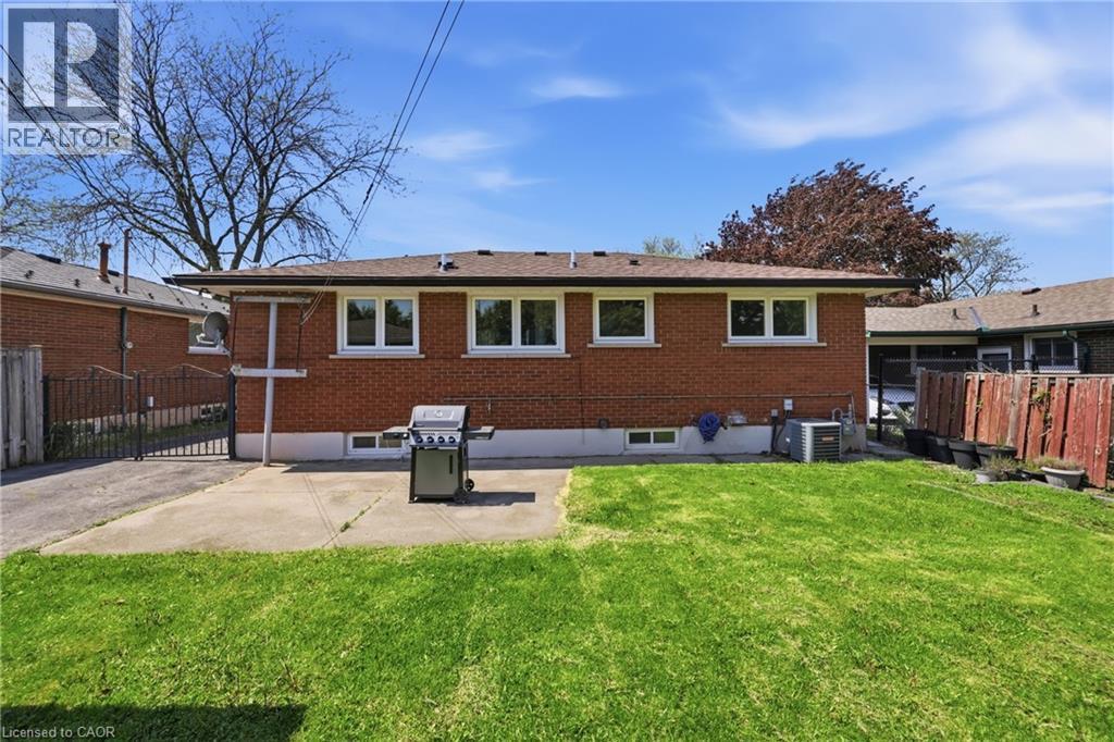 Rear exterior featuring a brick facade, white trim windows, and a concrete patio - 168 Nugent Drive, Hamilton, ON - Outdoor With Exterior