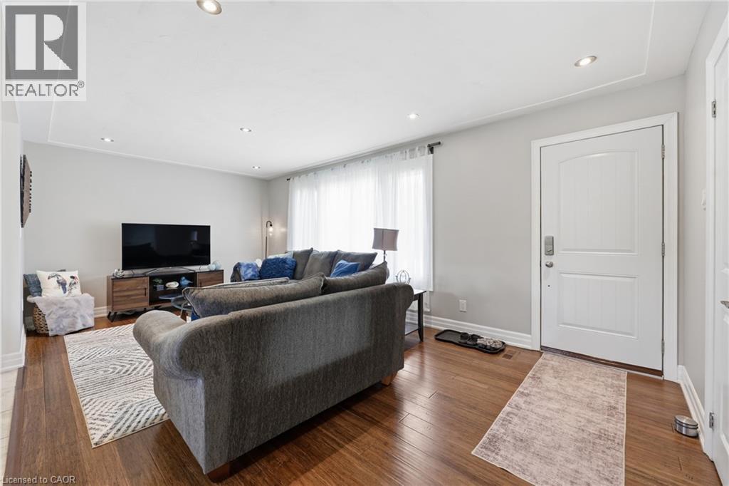 Hardwood-finish flooring throughout, recessed ceiling lighting, and a white paneled entry door with modern hardware - 168 Nugent Drive, Hamilton, ON - Indoor Photo Showing Living Room