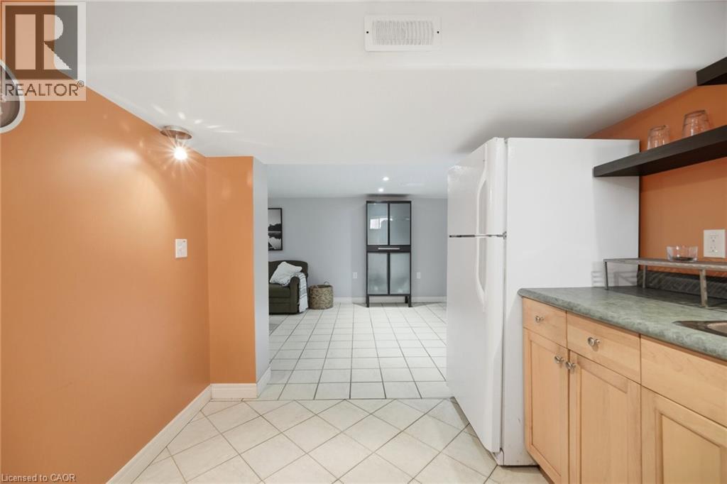 Kitchenette featuring light wood-finish cabinetry, a white refrigerator, a dark countertop, and open shelving - 94 Clarendon Avenue, Hamilton, ON - Indoor Photo Showing Kitchen
