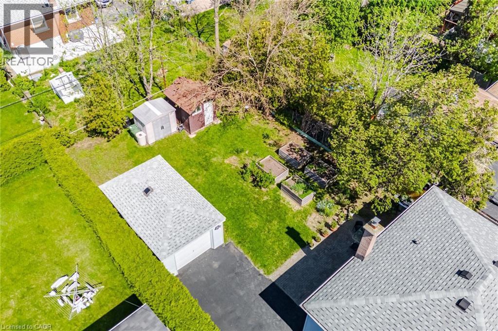 Expansive property featuring a detached garage with asphalt driveway, two distinct outbuildings, and multiple raised garden beds - 94 Clarendon Avenue, Hamilton, ON - Outdoor