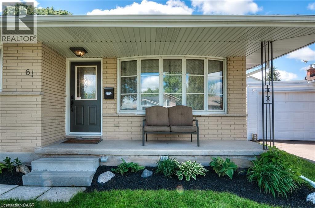Light-colored brick exterior featuring a covered porch, dark entry door, and a prominent bay window - 61 Bosworth Crescent Unit# Upper, Kitchener, ON - Outdoor With Deck Patio Veranda