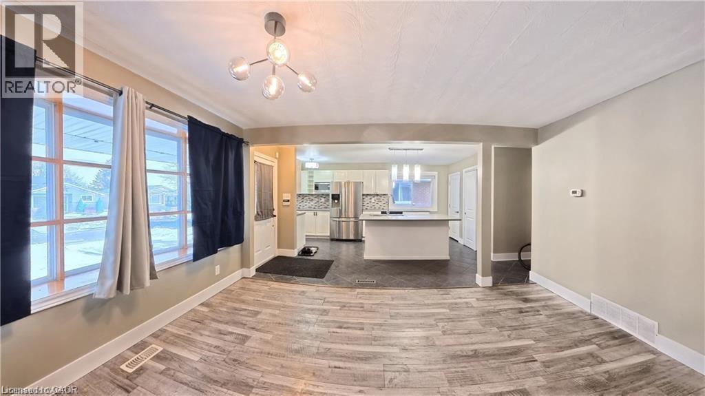 Open-concept living area featuring light wood-finish flooring, a modern chandelier, and a wide entryway to the kitchen - 61 Bosworth Crescent Unit# Upper, Kitchener, ON - Indoor Photo Showing Other Room