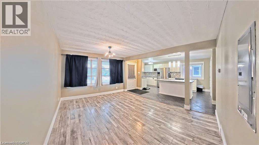 Living area featuring wood-finish flooring, multiple windows, and a ceiling-mounted light fixture - 61 Bosworth Crescent Unit# Upper, Kitchener, ON - Indoor