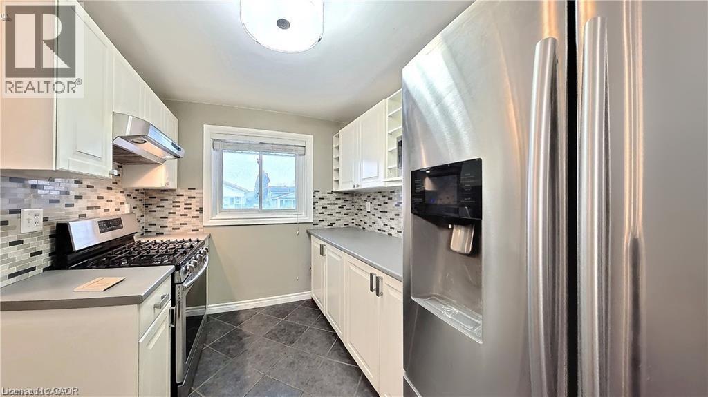 Kitchen featuring white cabinetry, grey countertops, stainless steel appliances including a gas range and French door refrigerator, mosaic tile backsplash, and dark tile flooring - 61 Bosworth Crescent Unit# Upper, Kitchener, ON - Indoor Photo Showing Kitchen With Stainless Steel Kitchen With Upgraded Kitchen